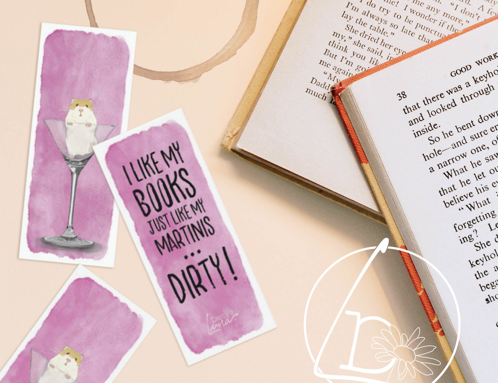Bookmarks and books on a table. Both front and back of the bookmarks have a pink watercolour background. The front has a russian hamster sitting in a martini glass. The back has the slogan "I like my books just like my martinis... dirty!"