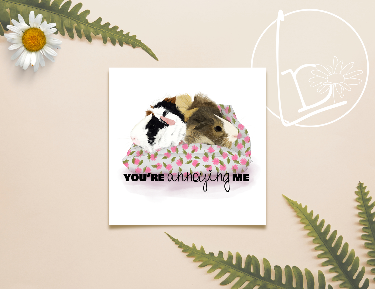 Illustration of two guinea pigs sitting next to each other on a cushion, but pointedly looking away from each other. One is ginger, white and black, the other is blonde and brown. The cushion is white with pink flowers and green leaves. The text reads "You're annoying me"