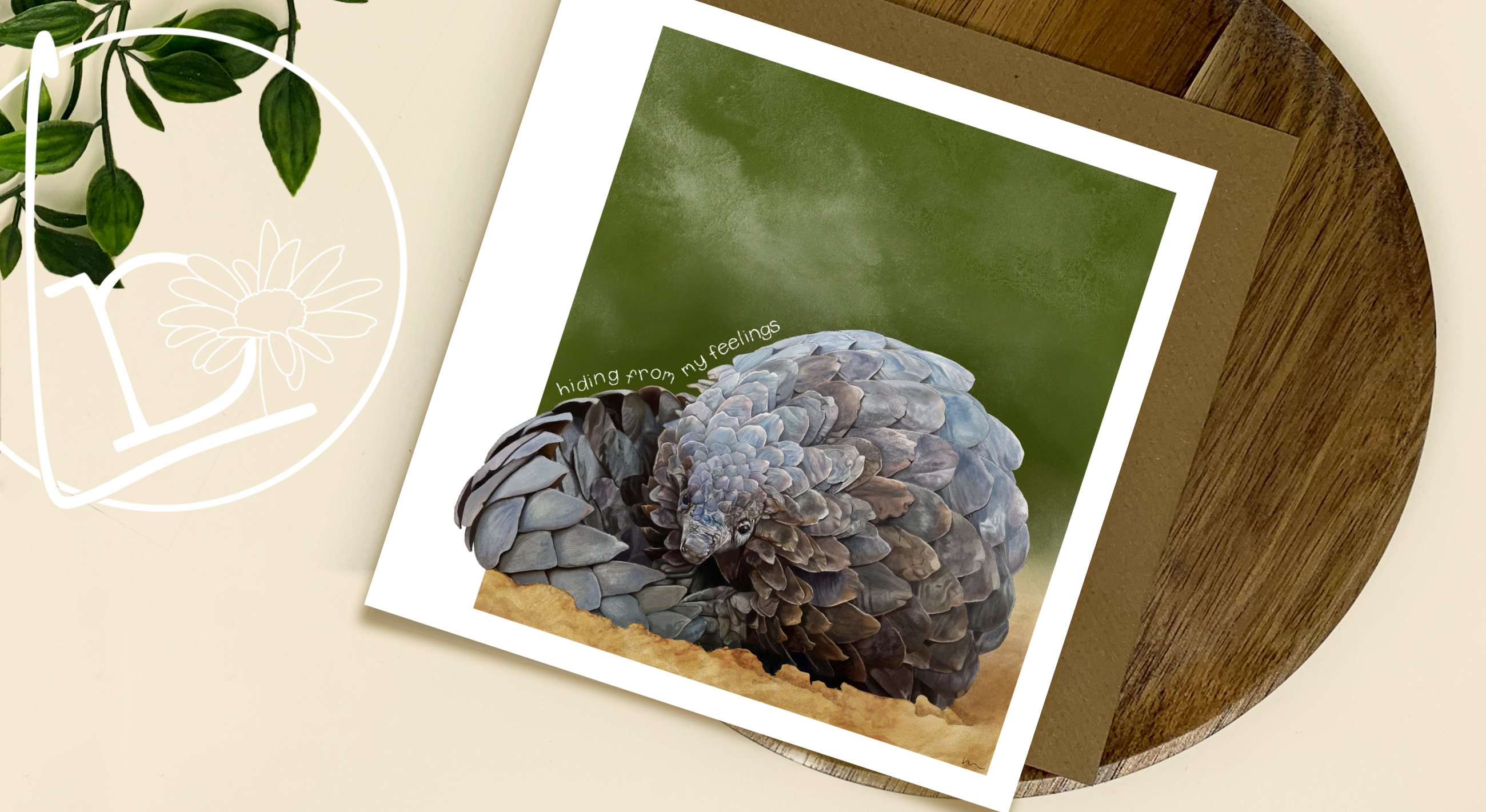 Card with a pangolin on a wooden surface with a plant in the corner.