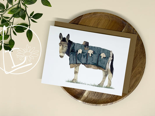 Illustrated card of a donkey carrying 3 lambs the pockets of his coat. 